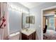 Bathroom featuring vanity lighting, a shower, tile surround mirror, and an open doorway at 13829 Timberland Dr # 204, Orlando, FL 32824