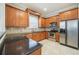 A modern kitchen featuring wood cabinets, dark countertops, stainless steel appliances, and tiled floors at 1545 Indiana Ave # B, Winter Park, FL 32789