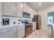 Modern kitchen with stainless steel appliances, quartz countertops and view into hallway at 1860 Tohoqua Blvd, Kissimmee, FL 34744