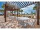 Outdoor patio area with modern tables and chairs under a pergola, with views of the community pool at 1860 Tohoqua Blvd, Kissimmee, FL 34744