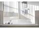 Bright bathroom showcasing a soaking tub with chrome fixtures beneath a window with white blinds and artwork at 240 Minniehaha Cir, Haines City, FL 33844