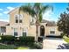 Inviting two-story home featuring a well-manicured lawn, lush landscaping, and a mature palm tree at 240 Minniehaha Cir, Haines City, FL 33844