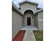 Close up of the front door with a covered porch, and red mulch adding a pop of color at 304 Lake Daisy Loop, Winter Haven, FL 33884