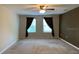 Bedroom featuring a ceiling fan, neutral walls and carpet, and two large windows with dark curtains at 3742 Maidencain St, Clermont, FL 34714