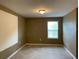 Bedroom with beige carpet and walls, featuring a window with horizontal blinds, offering a relaxing space at 3742 Maidencain St, Clermont, FL 34714