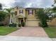 Two story home with tan exterior, red shutters, brick driveway, and two-car garage at 3742 Maidencain St, Clermont, FL 34714