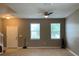 Neutral living room with ceiling fan, light-colored carpet, and large windows with horizontal blinds at 3742 Maidencain St, Clermont, FL 34714