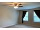 Bedroom features a ceiling fan, neutral walls and carpet, and two large windows with dark curtains at 3742 Maidencain St, Clermont, FL 34714