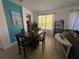 Bright dining room features a wooden table set, blue accent wall, and natural light from the window at 375 Orange Cosmos Blvd, Davenport, FL 33837