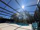 Screened-in pool with sunny skies and trees in the background offers a serene spot for relaxation and recreation at 375 Orange Cosmos Blvd, Davenport, FL 33837