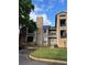 Three-story condo building with beige siding and brick accents, including a small landscaped area at 4200 Thornbriar Ln # 208, Orlando, FL 32822