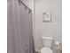 Neutral colored bathroom, featuring a toilet and tub-shower combination with gray, patterned curtain at 6808 Cranes Roost Rd, Harmony, FL 34773