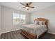 Comfortable bedroom with wood-look floors, a ceiling fan, and large window at 6808 Cranes Roost Rd, Harmony, FL 34773