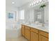 Bright bathroom featuring double sinks with wood cabinets, a soaking tub and glass enclosed shower at 8595 Sunrise Key Dr, Kissimmee, FL 34747