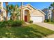 Charming single-Gathering home featuring a two-car garage, red door, lush landscaping, and tropical palm trees at 8595 Sunrise Key Dr, Kissimmee, FL 34747