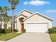 Inviting single-Gathering home featuring a lush front yard, a two-car garage, and a classic red front door at 8595 Sunrise Key Dr, Kissimmee, FL 34747