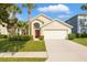 Charming single-story home features a well-manicured lawn, mature palm trees, and an attached two-car garage at 8595 Sunrise Key Dr, Kissimmee, FL 34747