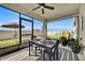 This screened-in patio features a ceiling fan, table and chairs, and view of the landscaped backyard at 1562 Delightful Dr, Davenport, FL 33896