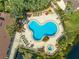 Aerial view of a community pool with lush landscaping, lounge chairs, and a hot tub at 8708 Papaya Dr, Kissimmee, FL 34747