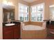 This bathroom offers a corner tub and a large window with plantation shutters at 10467 Henbury St, Orlando, FL 32832