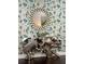 Silver table with a unique sculpture design and round mirror set against decorative wallpaper at 10467 Henbury St, Orlando, FL 32832