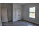 Bright bedroom with a closet, light-colored walls, a window, and gray wood-style tile flooring at 1313 Congo Dr, Kissimmee, FL 34759