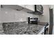 Close-up of granite countertops, stainless steel appliances, and white tile backsplash in kitchen at 1313 Congo Dr, Kissimmee, FL 34759