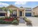 Charming tan home featuring a lush landscaped yard, front porch seating area, and a two-car garage at 13258 Vennetta Way, Windermere, FL 34786