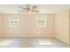 A bright, empty bedroom features light-colored walls, ceiling fan, and stylish light-colored flooring and windows at 15345 Rockridge Rd, Polk City, FL 33868