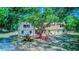 Charming home exterior featuring a large tree providing shade, a golf cart, and well-maintained landscaping at 15345 Rockridge Rd, Polk City, FL 33868
