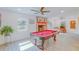Bright living room features a pool table, brick fireplace, ceiling fan, and natural light at 15345 Rockridge Rd, Polk City, FL 33868