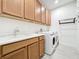 Well-lit laundry room features ample cabinet storage, a utility sink, and modern washer and dryer at 1930 Molise Dr, Poinciana, FL 34759