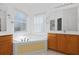 Bright bathroom featuring a jacuzzi tub, vanity, and wood cabinets with marine-themed wall decor at 196 Knoll Wood Dr, Kissimmee, FL 34759