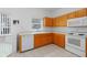 Kitchen with wood cabinets, white appliances, tile flooring, and natural light from window at 196 Knoll Wood Dr, Kissimmee, FL 34759