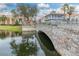 Scenic water view of a stone bridge over a tranquil pond, surrounded by lush greenery and colorful buildings at 196 Knoll Wood Dr, Kissimmee, FL 34759