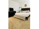 Well-lit bedroom with a dark wood headboard, neutral colored bedding, and a bench at the foot of the bed at 2641 Calistoga Ave, Kissimmee, FL 34741