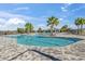 Community pool featuring a unique shape, palm trees, lounge chairs and a lake view at 3930 Palazzo Pl, Winter Haven, FL 33884