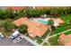 Aerial view of a community pool with Jacuzzi, surrounded by lush landscaping, parking, and community buildings with red tile roofs at 425 Fountainhead Cir # 107, Kissimmee, FL 34741