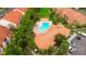 Aerial view of a community pool surrounded by lush landscaping, lounge chairs and community buildings with red tile roofs at 425 Fountainhead Cir # 107, Kissimmee, FL 34741