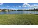 Expansive backyard with lush green grass and a peaceful lake view under a bright blue sky with fluffy clouds at 446 Davinci Pass, Poinciana, FL 34759