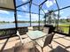 Enclosed patio features a dining set, outdoor kitchen, and a view of a tranquil lake at 446 Davinci Pass, Poinciana, FL 34759