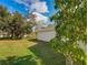 Expansive backyard with lush greenery, framed by mature trees and clear blue skies at 4941 Luna Negra Dr, Orlando, FL 32811