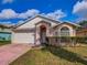 Well-kept single-story home featuring a two-car garage, arched entryway, and manicured landscaping at 4941 Luna Negra Dr, Orlando, FL 32811