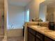 Bright bathroom featuring a soaking tub, glass shower, and double vanity with granite countertops at 499 Meadow Pointe Dr, Haines City, FL 33844