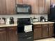 Well-lit kitchen features sleek black appliances, rich wooden cabinetry, and stylish countertops at 499 Meadow Pointe Dr, Haines City, FL 33844