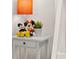 Bedroom decor of a white nightstand with a lamp, plant, and Mickey Mouse dolls at 5411 Oakgrain Ct, Davenport, FL 33837