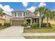 Charming two-story home with a well-manicured lawn and tropical landscaping, showcasing curb appeal at 5411 Oakgrain Ct, Davenport, FL 33837