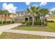 Two-story home with a driveway, manicured landscaping, and tropical palm trees enhancing its facade at 5411 Oakgrain Ct, Davenport, FL 33837