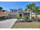 Charming two-story home with a well-manicured lawn, mature palm trees, and a two car garage at 5411 Oakgrain Ct, Davenport, FL 33837