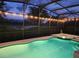 Enjoy a relaxing swim in this screened-in pool and hot tub under ambient string lights and a beautiful evening sky at 5411 Oakgrain Ct, Davenport, FL 33837